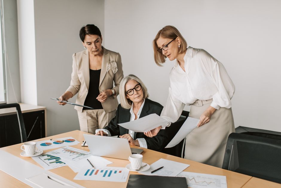 Three businesswomen discussing reports in a modern office environment