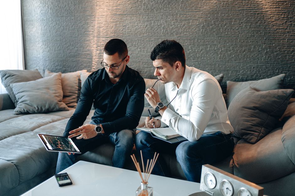 Dva poslovna profesionalca analiziraju financijske grafove na tabletu