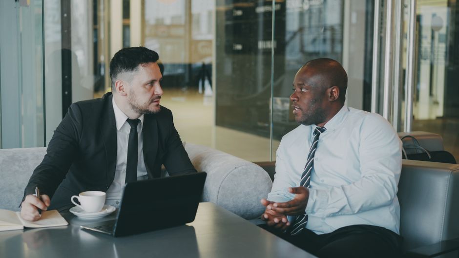 Two businessmen discussing at a cafe with a laptop and coffee